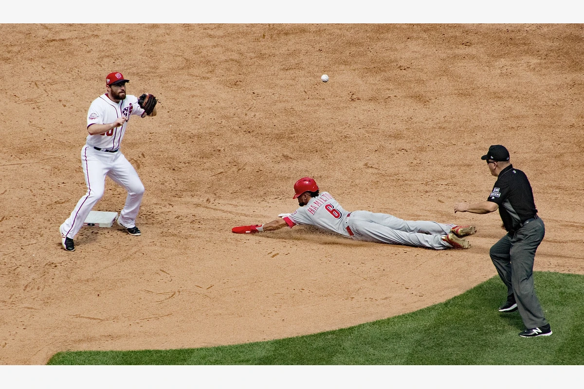 Baseball game action: Washington Nationals infielder Daniel Murphy (#10) fields near second base as Cincinnati Reds baserunner Billy Hamilton (#6) slides in, with the ball visible in the air and an umpire watching the play.